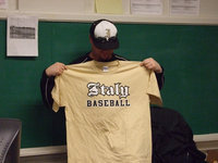Image: Coach Ward — Coach Ward holds up the t-shirt being sold by the baseball program.  The price is $12.00.