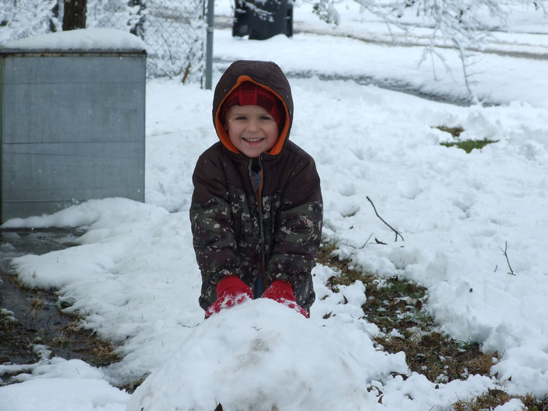 Image: Landon has a big smile — Four year old, Landon Torres, helps the Nash family with their large snowman.  He is in charge of the head.