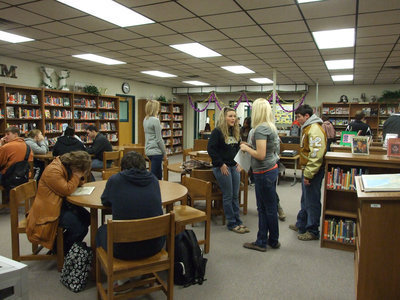 Image: Congregating in the library — The students visit in the library after Mardi Gras.
