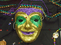 Image: Mask in the library case — A traditional mask you might see in New Orleans or Rio de Janeiro on Mardi Gras, made by Sharon Farmer.