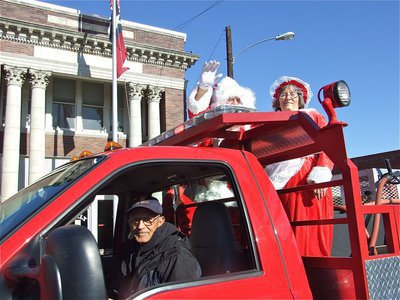 Image: Mommy, It’s Santa! — Santa and Mrs. Claus get a lift from Sal and the Italy volunteer Fire Department as they pass in front of Italy City Hall.