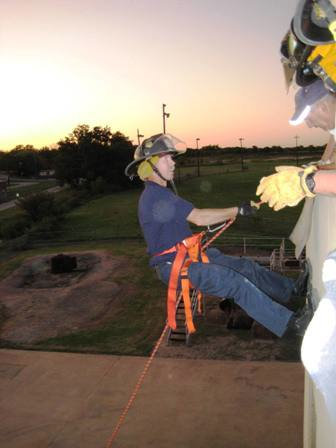 Image: Learning the ropes — Tommy Sutherland repels down the fire training building in Waxahachie while his classmates look on.