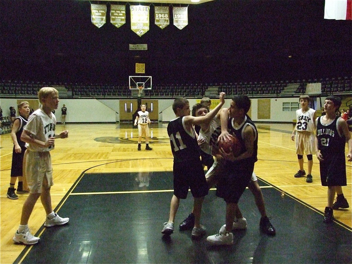 Image: Forcing a jump ball — Chace McGinnis(13) ties up a Bulldog under the basket.