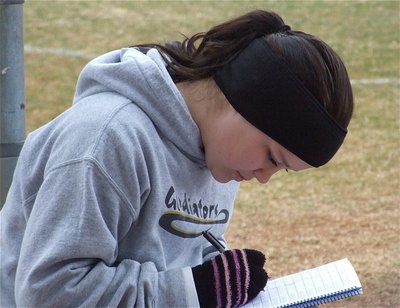 Image: Paige keeps track — Paige Westbrook tracks the game for the Lady Gladiators from the dugout.