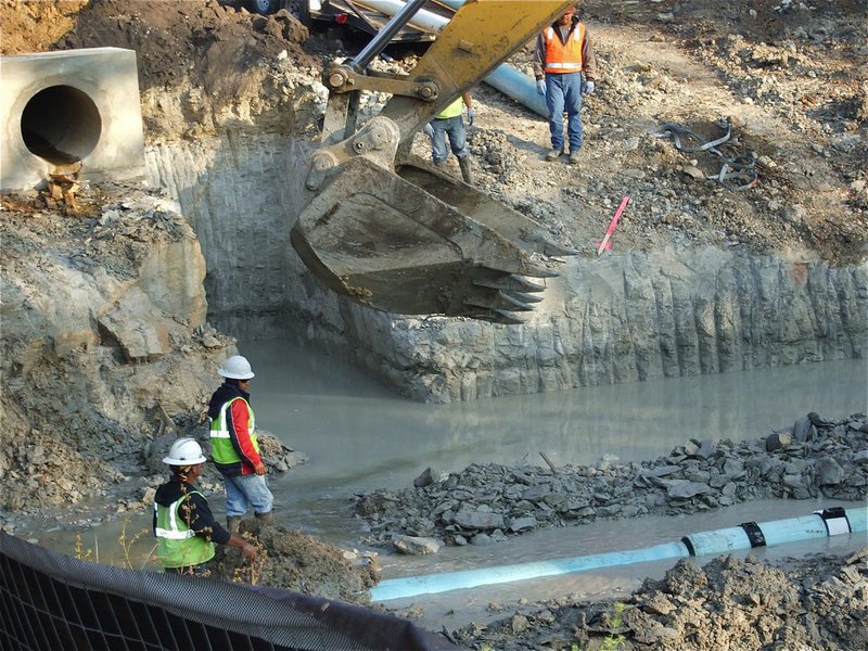 Image: A little help — Crews try to align the pipes with a little help from the big Cat.