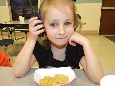 Image: I need backup… — Addy Mathers, the daughter of April and Jody Mathers, radios for backup at the PTO dinner and silent auction.