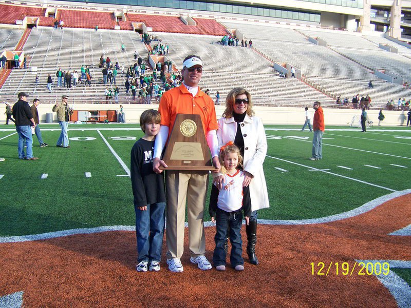 Image: Daniel Seay with his wife Robin and their kids Grant(9) and Skyler(4) — Defensive Coordinator Daniel Seay poses for pictures with his family at midfield, inside UT stadium, while holding the 4A State Championship trophy won by Daniel and his Aledo Bearcats football team on December 19, 2009.