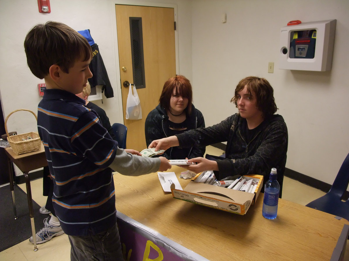 Image: Give Me Chocolate! — Ryan Connor purchases a bar of chocolate in support of the Italy Band members, plus, he just wanted some chocolate.