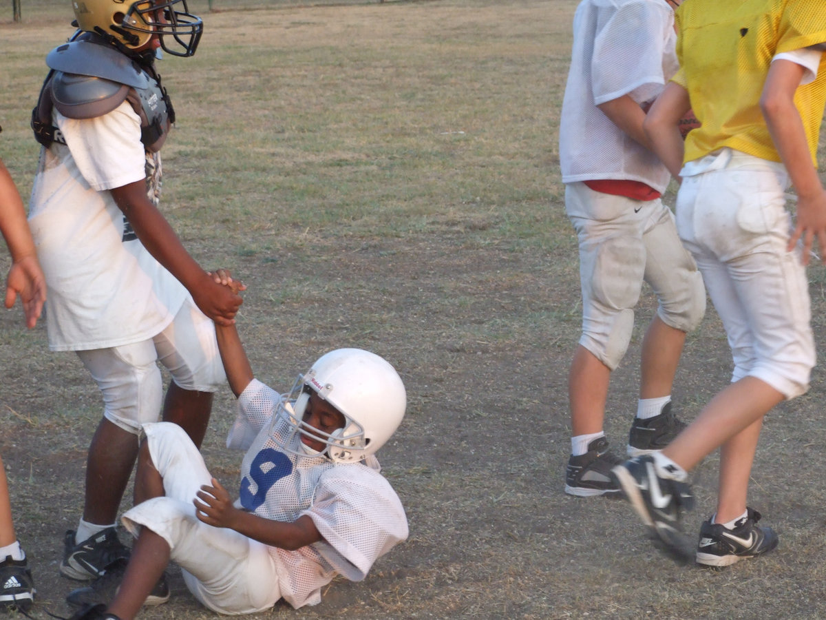 Image: Bigs helping smalls — Major tailback, Ken Norwood, Jr., helps up one of the Minors during their scrimmage against one another. We’re all in this together.