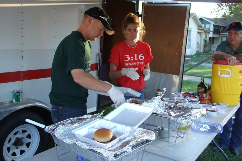 Image: BBQ for sale — Michael Chambers, Ronda Cockerham package dinner to go for hungry customers as Fire Chief Don Chambers looks on.