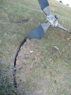 Image: Gashed ground — A shot of the propeller after it broke away from the nose of the aircraft and sliced into the pasture.