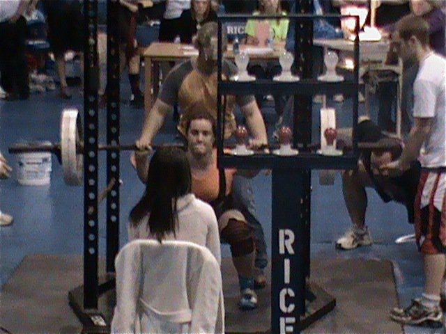 Image: Kaitlyn Bales — Kaytlyn Bales competes in the squat as coach Craig Bales kneels down to make sure she drops down far enough.