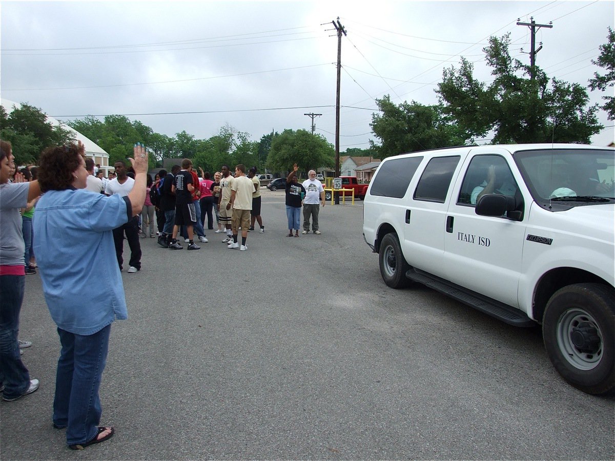 Image: One last wave — The Italy High School student body and faculty members give John Isaac, Stephen Coleman and Craig Bales one final wave as the trio exits the IHS parking lot on their way to the State track meet in Austin.