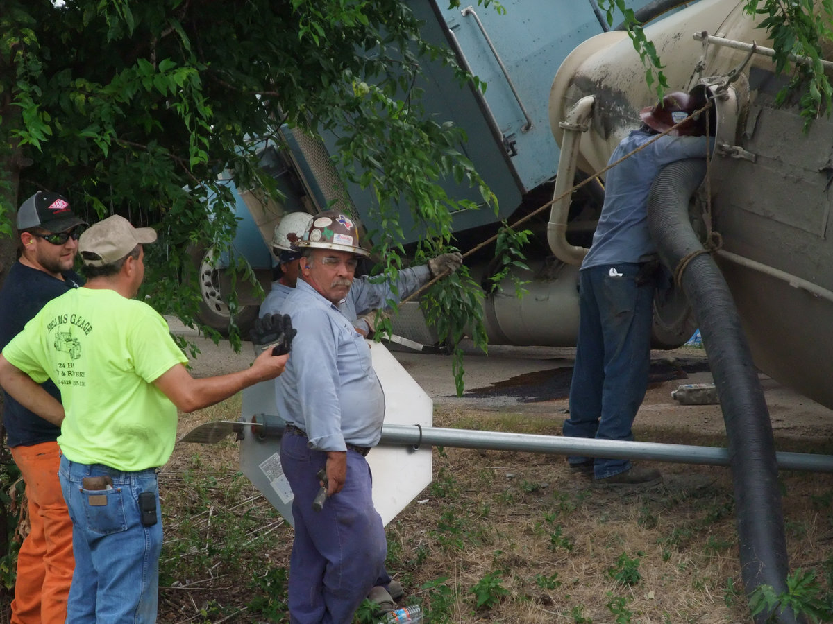 Image: Vacuum job — Crews vacuum the powdered cement mix from the stranded 18-wheeler and later pump it into a second 18-wheeler that hauled the mix to its intended destination.