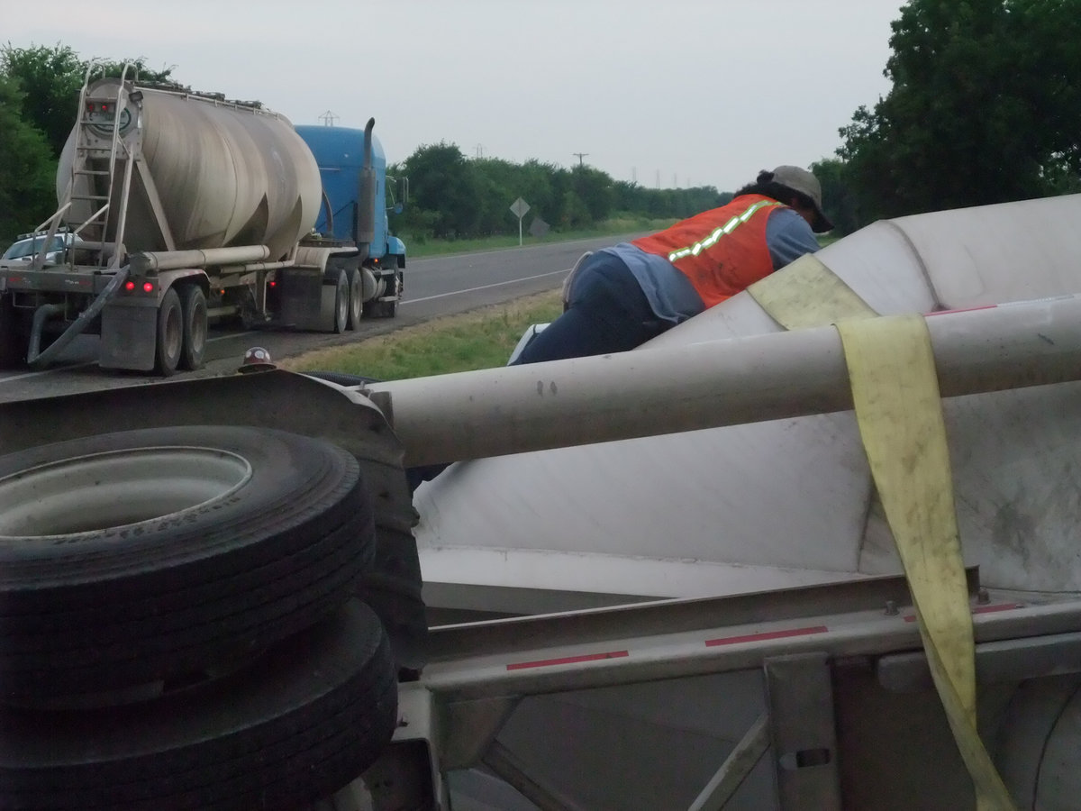 Image: Risk taker — Jesus Martinez is at it again. This time, he lays across the side of the fallen trailer to hook the straps that will lift the trailer from the ditch.