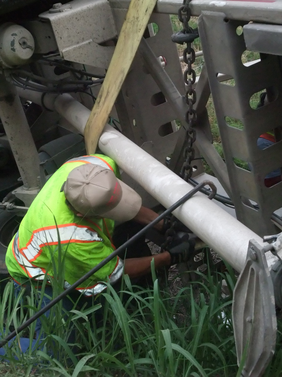 Image: Hooking the chains — Keith Helms hooks the chains around the trailer just moments before hoisting it from the ditch.