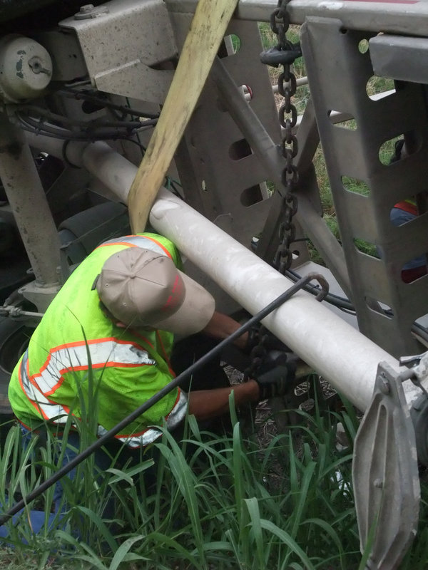 Image: Hooking the chains — Keith Helms hooks the chains around the trailer just moments before hoisting it from the ditch.