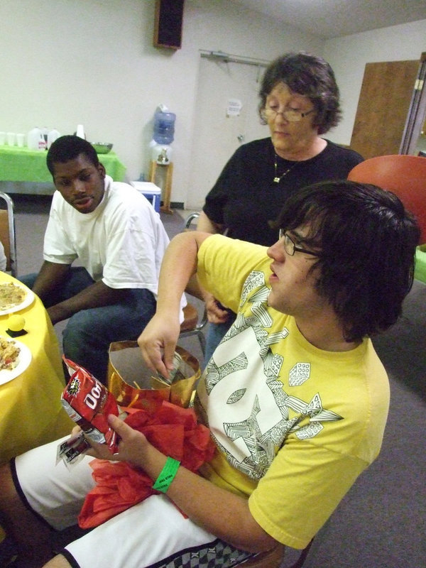 Image: Trevor wins money — Karen Mathiowetz and Curtis Cole watch as Trevor opens his prize.