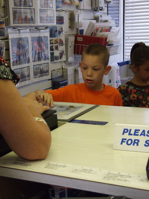 Image: Buying Stamps — This young man was using his money skills in purchasing a stamp.