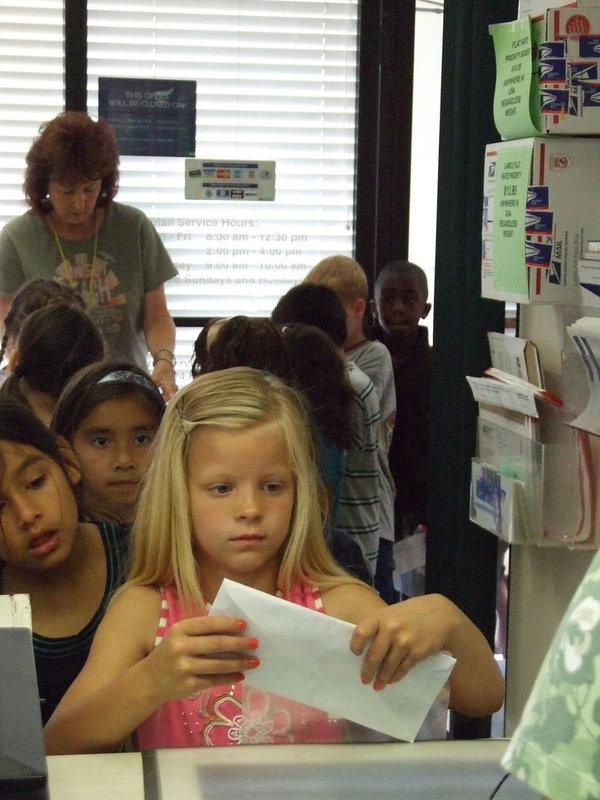 Image: Let’s Mail This Letter — This young lady is making sure everything is correct on her envelope before she hands it in to be mailed.