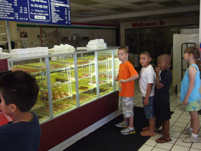 Image: Lined Up And Waiting — They are waiting their turn to purchase their donuts.