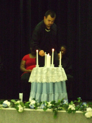 Image: Lighting the Candles — The middle candle stands for knowledge and the other four candles represent: scholarship, leadership, service and character.