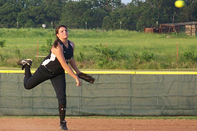 Image: ….do it all ! — Cori performs the “stanky leg” dance while making a throw to first base.