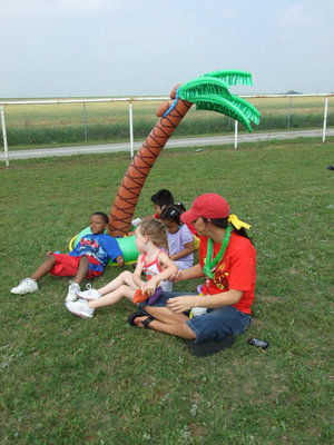 Image: Miss Dickerson and Students — They are enjoying the tropical breezes under the palm tree.