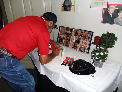 Image: Mark Souder signs card — A card to sign, a photo album and a picture of Don and his lovely wife Kay greeted well wishers as they entered the party.