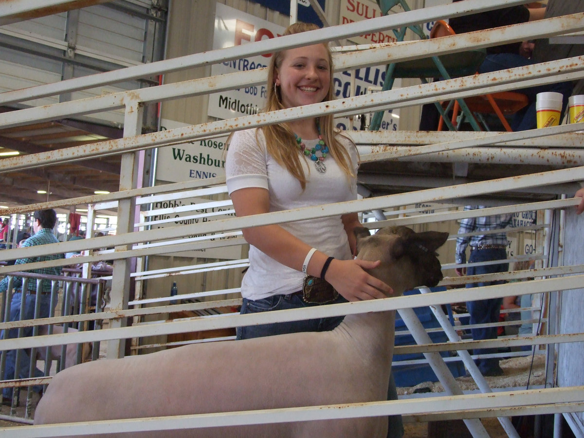Image: Jaclynn Lewis gives a smile — Jac and her lamb are in the chute ready for the sale.