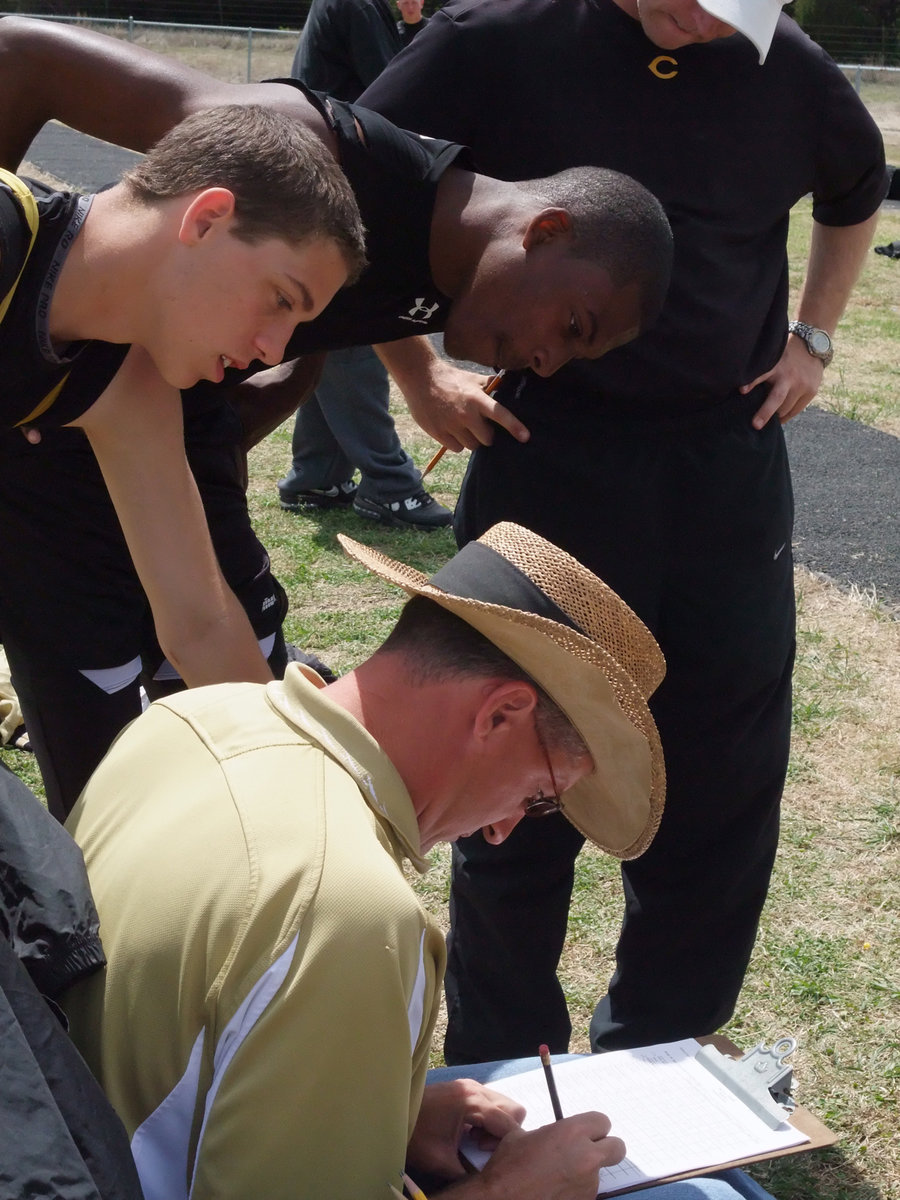 Image: Awaiting the results — Brandon Souder and John Isaac glance over Italy Coach Kyle Holley for their results in the triple jump.