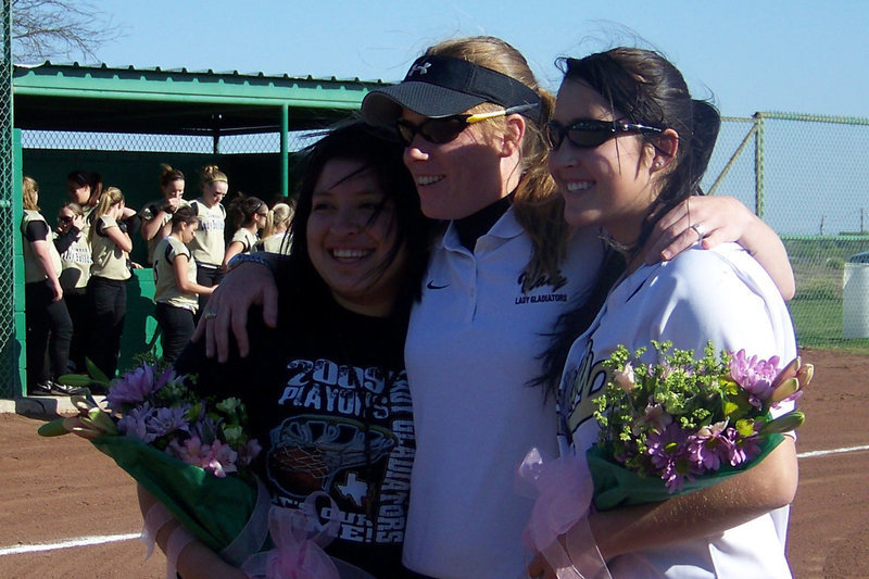 Image: Senior night photo opps — Seniors Angelica Garza and Blanca Figueroa take pictures with Head Coach Jennifer Reeves during the pre-game ceremony.