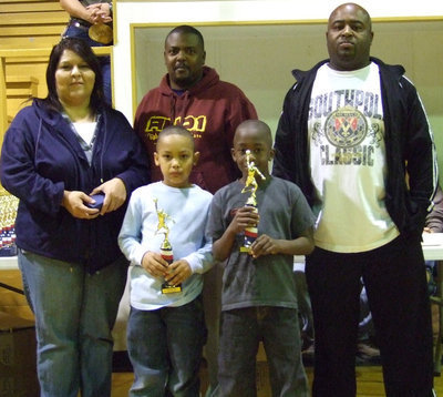 Image: C.C. &amp; Jacob — Cornelius Jones and Jacob Davis represent their teammates as they accept their 1st Place trophies along with their coaches Michelle on the left and Maylen on the right and Commissioner Glen “Kilroy wuz here” McKlendon in the middle.