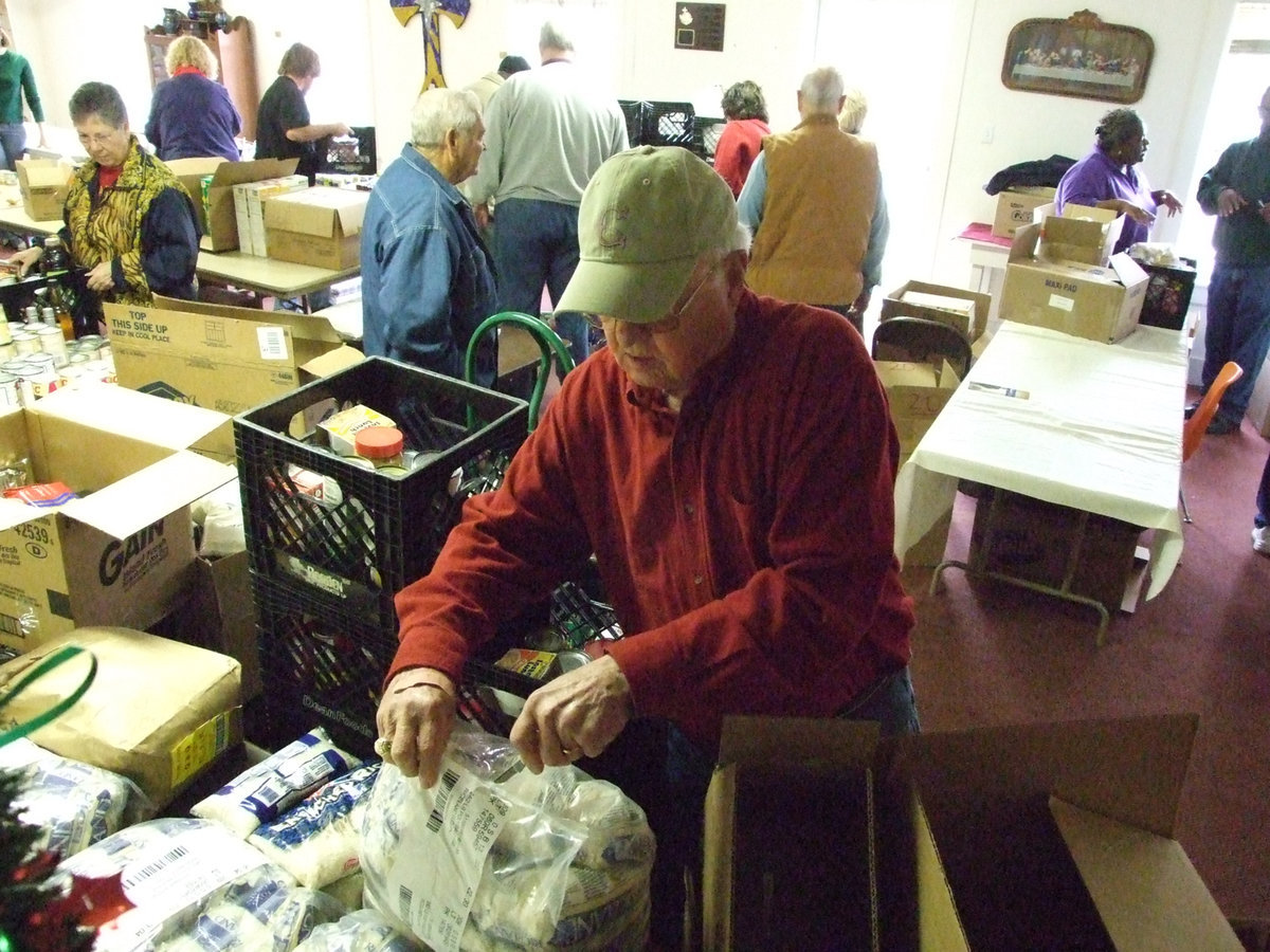 Image: Rice for everyone — Kenneth Crowell opens bags of rice for the Christmas basket delivery for Italy residents.  The Italy Ministerial Alliance delivers food and turkeys every year to people in need.