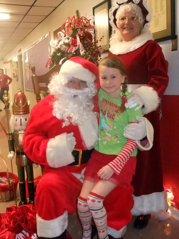 Image: Kimberly Hooker — Kimberly, Santa and Mrs Claus. Kimberly said, “It is fun sitting with Santa.”