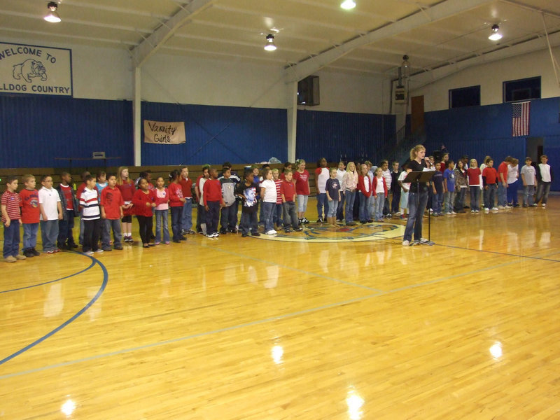 Image: Laura Harvey Welcoming Guests — Milford 2nd through 5th grades ready to sing.