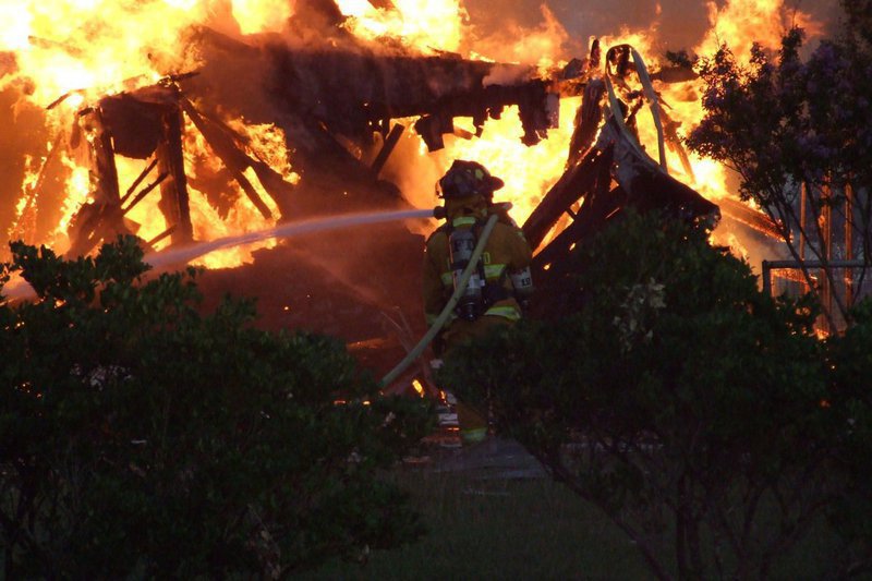 Image: Water conquers fire — Members of the Italy Volunteer Fire Department hose down the burning debris.