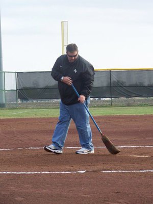 Image: THANKS COACH COKER!!! — Head Baseball Coach Matt Coker offered his time and expertise last week in adding clay to the very “soft” softball field. He is shown here tweaking the pitchers circle before the game.