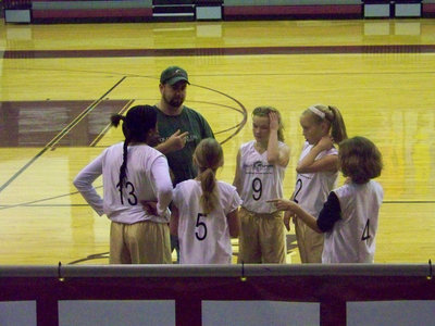 Image: Coach “B” and the Girls — Coach Barry helps the girls get their assignments straightened out before entering the game.