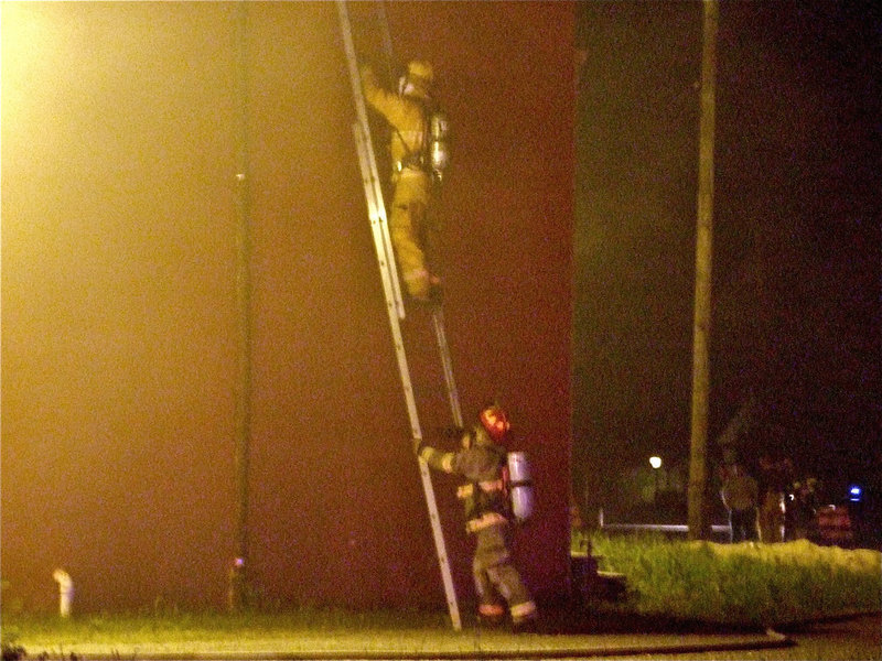 Image: Climbing to the roof — Milford firefighters make their way up to the rooftops to begin the aerial assault on the fire.