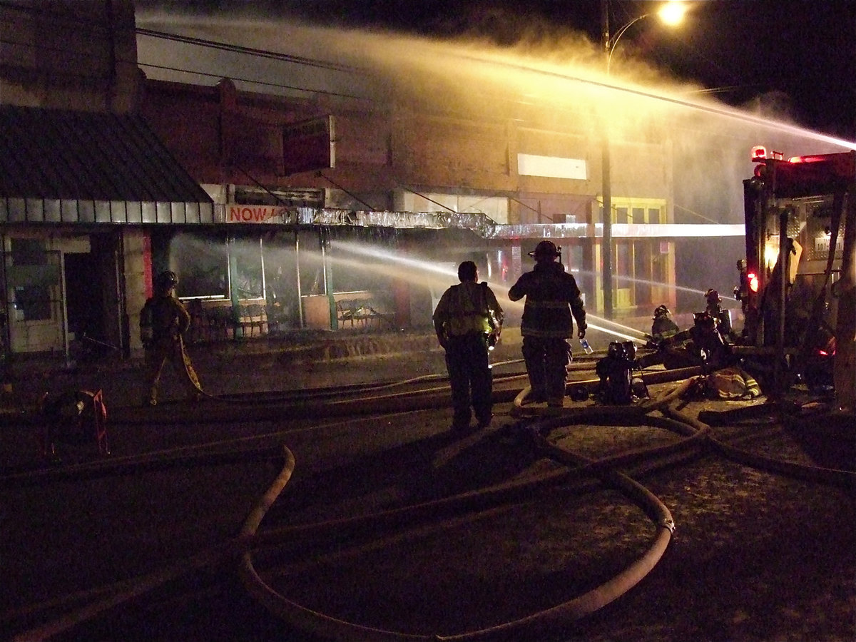 Image: Still battling — Fire crews keep the water flowing to help douse the remaining hot spots.