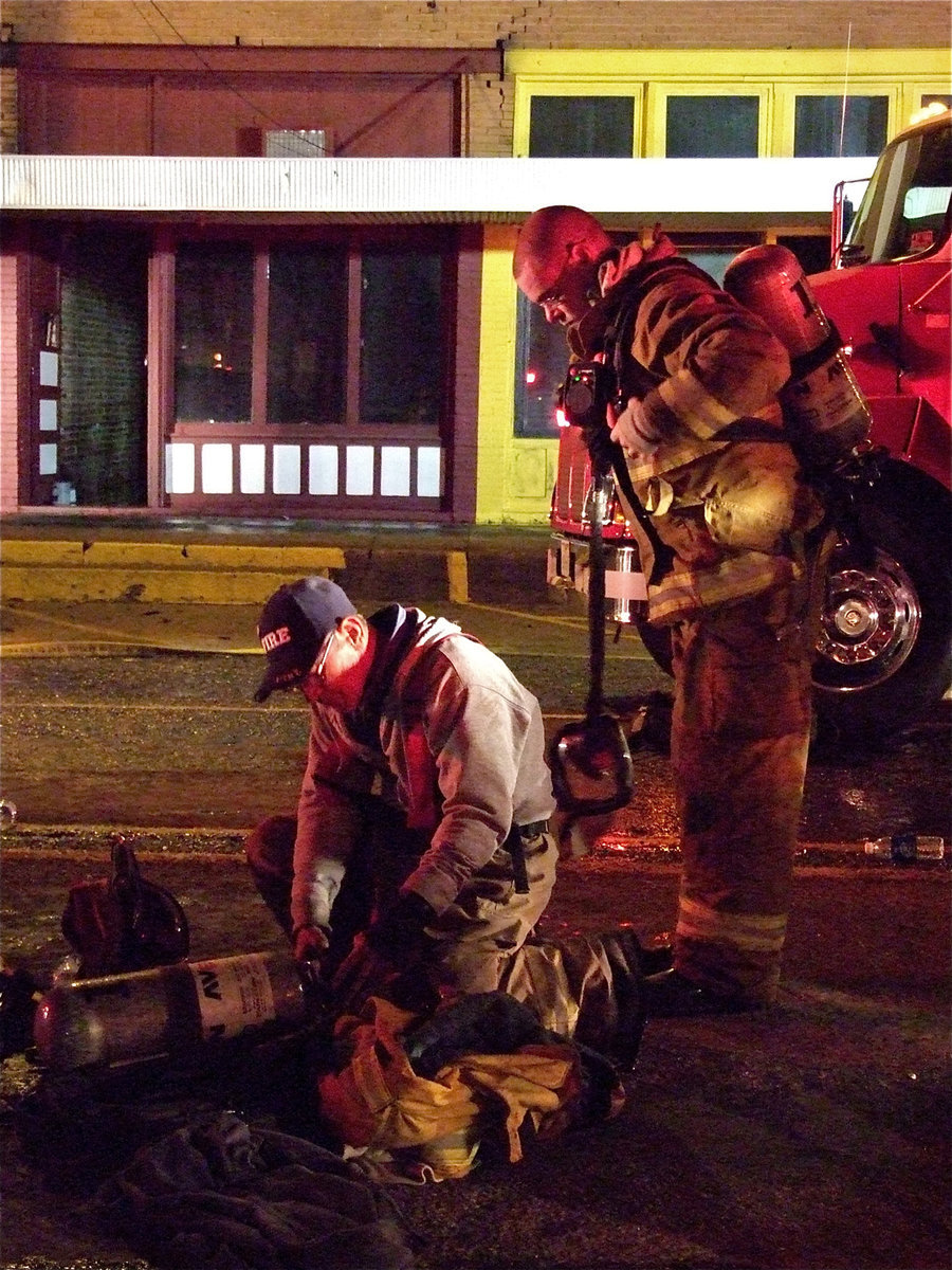 Image: Non-stop action — Sal Perales continues to outfit firefighters with the needed equipment as Italy firefighter, Brad Chambers, prepares to re-enter the buildings.