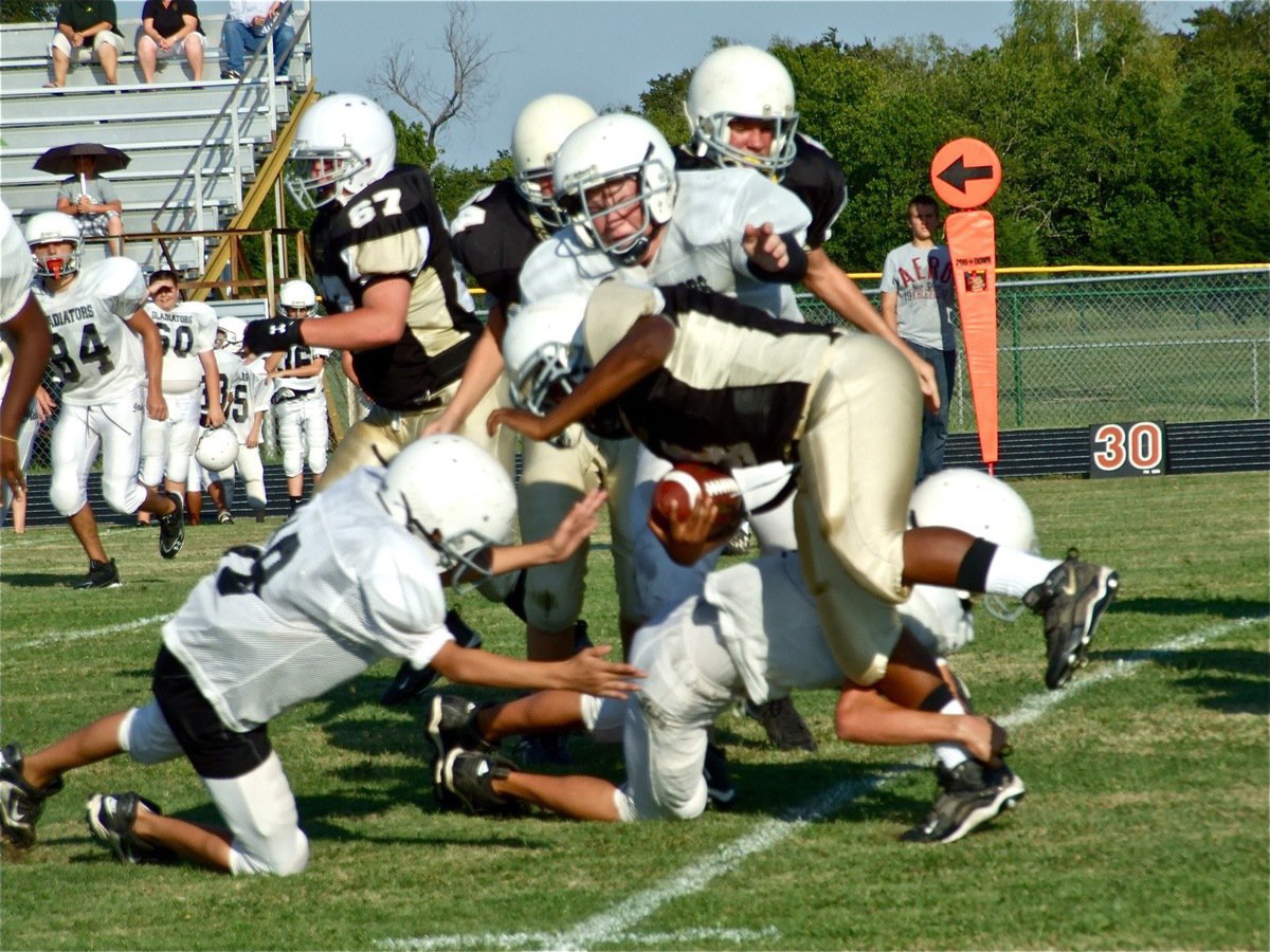 Image: Group tackle — Several of Italy’s Junior High players combine to bring down the Jaguar back.