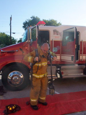 Image: Fireman Brad Chambers  — Fireman Chambers was putting on the fire gear and explaining about it to the students.
