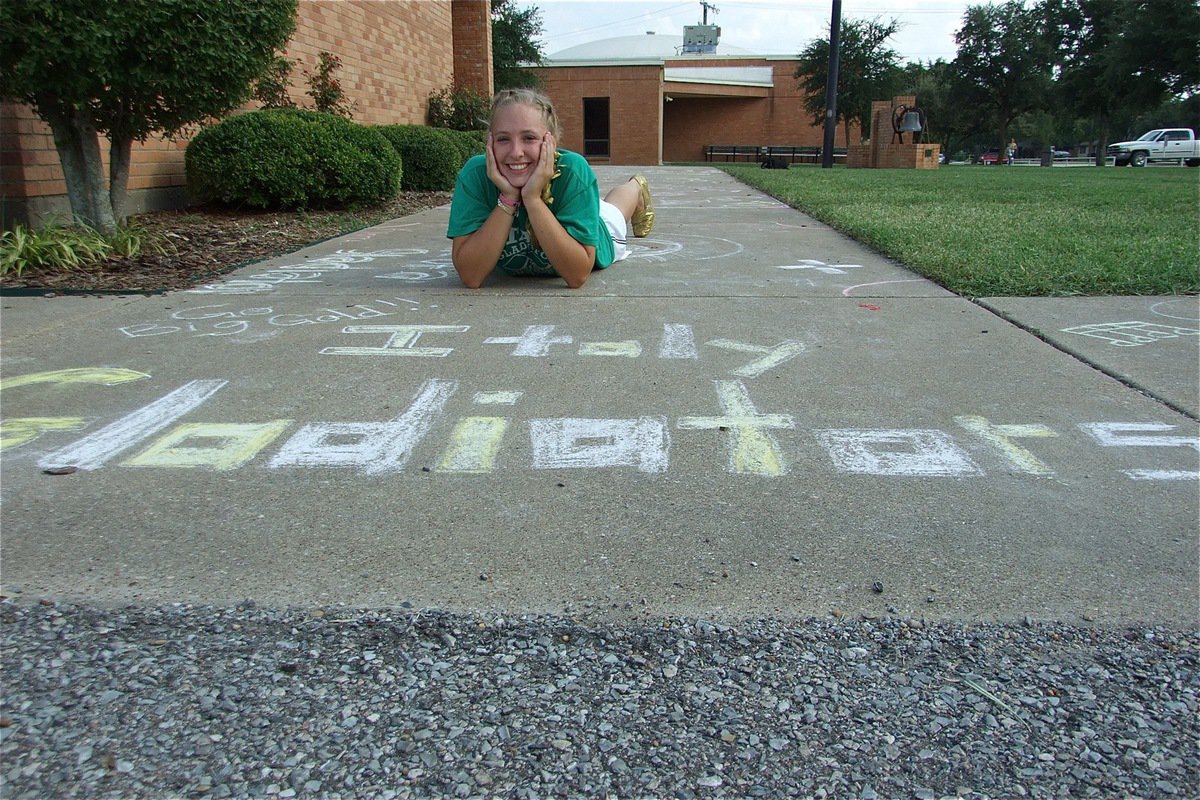 Image: Chalk the walk — 8th grader Jaclynn Lewis poses with her section of the sidewalk she decorated in front of the Administration Building at the Italy High School campus to celebrate homecoming week and to welcome back alumni.