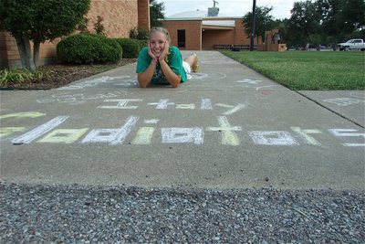 Image: Chalk the walk — 8th grader Jaclynn Lewis poses with her section of the sidewalk she decorated in front of the Administration Building at the Italy High School campus to celebrate homecoming week and to welcome back alumni.