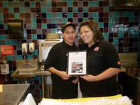 Image: Texas Best Smiles — Accepting a framed, “Thank you,” for their participation in the Monolithic compost cover testing project are “Texas Best Smokehouse" employees Albert Estrada and Rosie Duron.