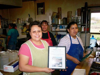 Image: Mamma’s Place Pitches In — Juanita “Mamma” Martinez, owner of “Mamma’s Place” in Italy, Texas,  pauses from cooking her famous breakfast burritos to receive a framed "Thank you” for her restaurant’s participation in the Monolithic compost cover testing project. Also pictured are: Martha Salazar, Margarita Salazar &amp; Gloria Quintero.