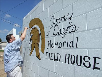 Image: Honoring Jimmy Davis — Local artist and a graduate of Italy High School, Ray Don Mitchell paints a Gladiator Head and the words, “Jimmy Davis Memorial Field House”, on the Italy Gladiators locker room.