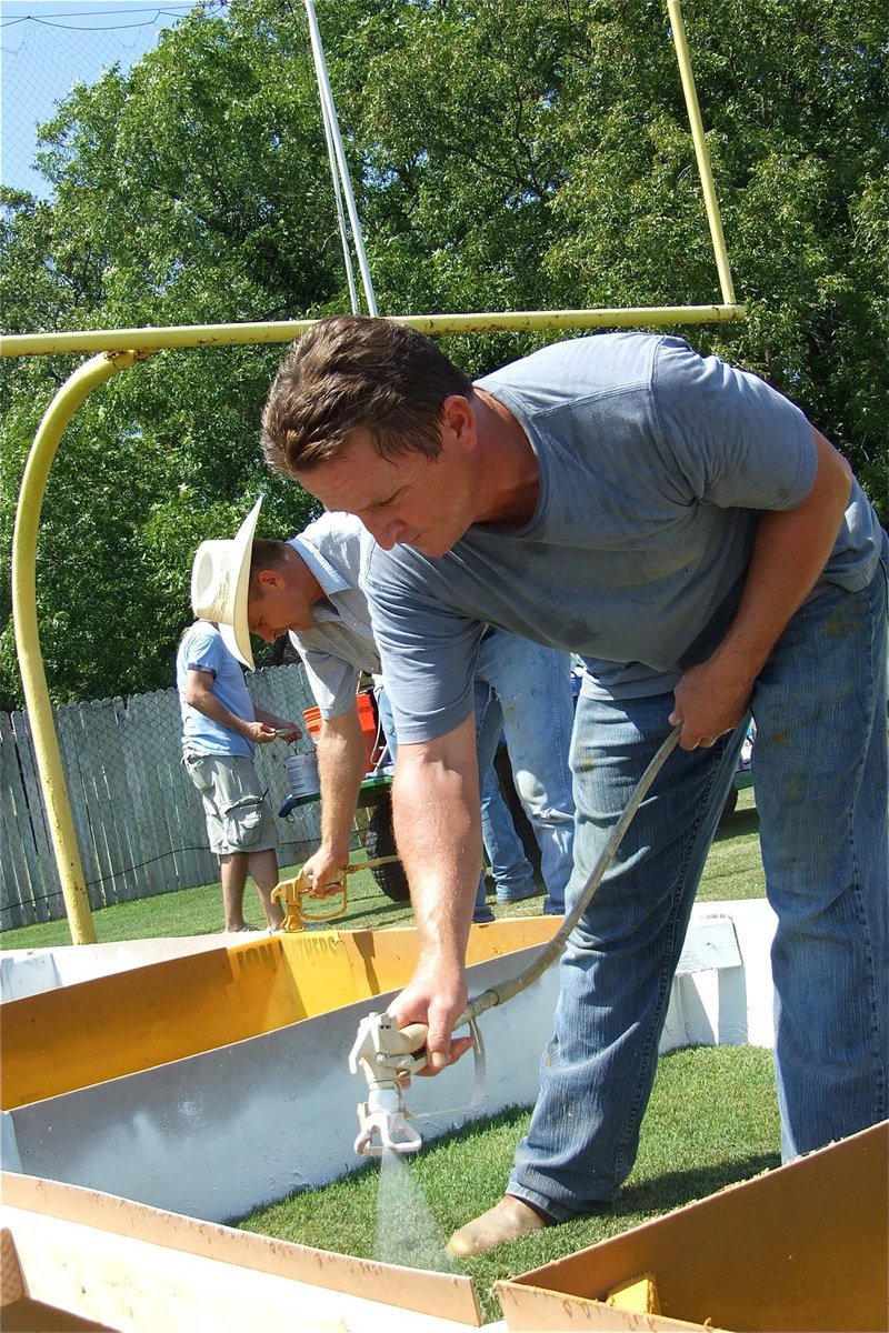 Image: Still spraying — Curtis Riddle and Jon Mathers keep at it with the Homecoming game just one day away.